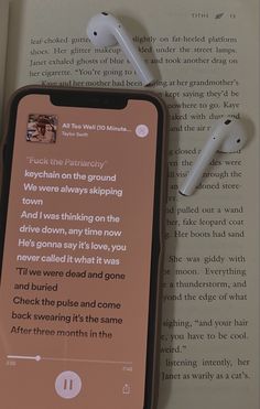 an open book with earbuds laying on top of it next to an iphone