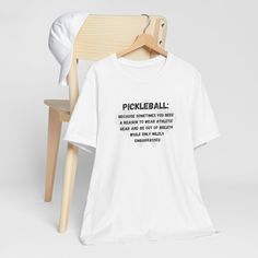 a white t - shirt with the words pickleball on it next to a wooden chair