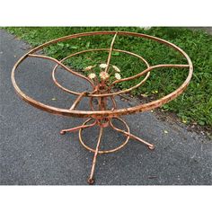 an old metal table with four circular sections and flowers on the top, sitting in front of some grass