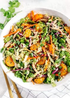 a salad in a white bowl with oranges and shredded lettuce on the side