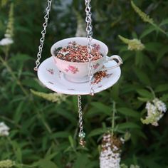 a teacup filled with bird seed hanging from a chain