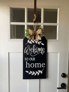 a welcome to our home sign hanging on the front door with a bow and ribbon