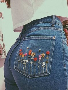 the back of a woman's jeans with embroidered flowers on it and a cell phone in her pocket