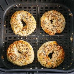 four bagels sitting on top of a black grill in a pan with sesame seeds