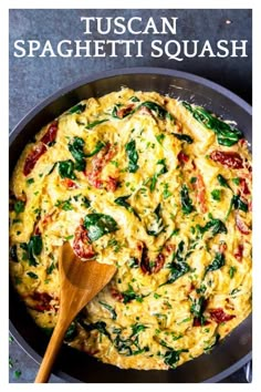 a pan filled with spinach and cheese on top of a table next to a wooden spoon