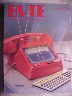 an old red telephone sitting on top of a table next to a keyboard and mouse