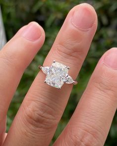 a close up of a person's hand with a diamond ring on their finger