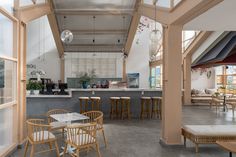 the interior of a restaurant with tables, chairs and stools in front of an open window