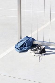 a pair of black and white shoes sitting on the ground next to a fence