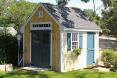 a small shed sitting in the middle of a yard with grass and trees around it