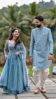 a man and woman dressed in blue standing next to each other on a wooden walkway