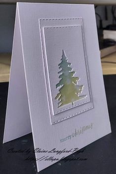 a white card with a green christmas tree on the front and bottom, sitting on top of a table