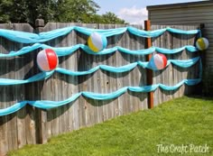 an inflatable water slide on the side of a fence with balloons attached to it