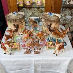 a table topped with figurines and deers on top of a white table cloth