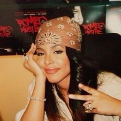 a woman with long hair wearing a bandana and holding her hand up to her face