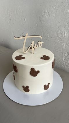 a white cake with brown polka dots and the word tuo on top is sitting on a plate