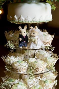 a tiered cake with cupcakes on it and two mice figurines