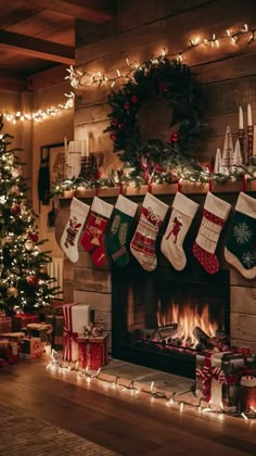 christmas stockings hung over a fireplace with presents under it and lights on the mantel