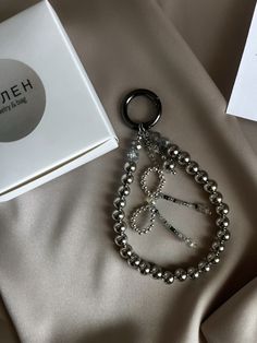 a silver beaded bracelet with an open box next to it on a satin surface