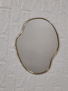 a mirror that is on the wall in front of a white tiled wall with gold trim