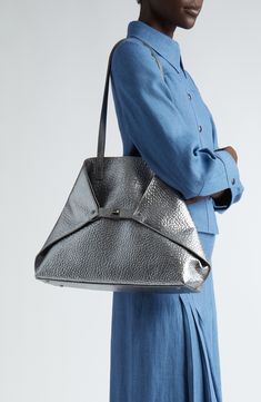 A hammered texture deepens the shine of this silvery calfskin bag that can be carried as a classic shopper or cinched for a signature trapezoidal silhouette. An interior zip pouch handily secures smaller items. Open top Tuck-in turnlock straps Top handles; removable shoulder strap Interior zip and wall pockets; removable top-zip pouch Leather Made in Italy Designer Handbags Modern Silver Shoulder Bag For Formal Events, Luxury Metallic Silver Shoulder Bag, Silver Rectangular Bag For Everyday Luxury, Silver Rectangular Bags For Everyday Luxury, Silver Luxury Shoulder Bag For Everyday, Modern Silver Bags For Formal Occasions, Luxury Metallic Shoulder Bag For Shopping, Silver Leather Top Handle Shoulder Bag, Luxury Metallic Shoulder Bag With Palladium Hardware