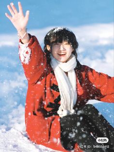 a woman sitting in the snow with her hand up