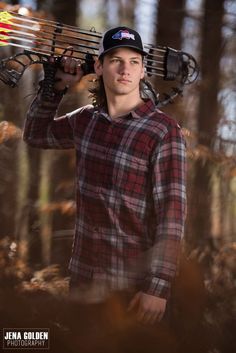 a young man is holding his skis over his head while standing in the woods