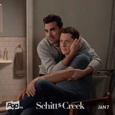 two men hugging each other while sitting in a bathroom with the caption schits creek