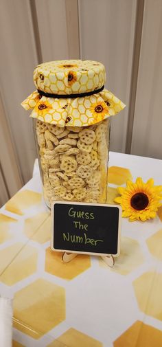 a jar filled with cookies sitting on top of a table next to a sunflower