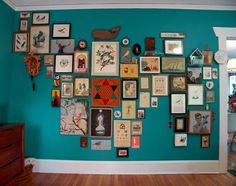 there is a wall with many different pictures on it in this room, and the walls are painted teal blue