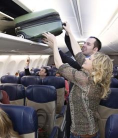 two people on an airplane with their arms in the air and one person holding a suitcase