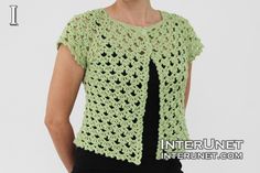 a woman wearing a green crocheted vest and black pants with her hands on her hips