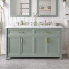 a bathroom vanity with two mirrors above it and gold handles on the sinks, along with other accessories