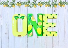 the word'one'is made out of plastic lemons and green leaves on a white wooden background