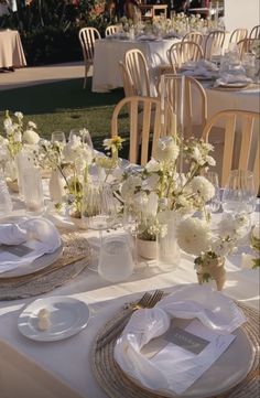 the table is set with white flowers and place settings