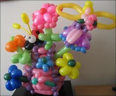 a bunch of balloons that are in the shape of animals and flowers on a table