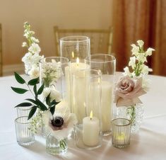 there are many different vases with flowers and candles on the table in front of them