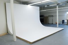 an empty room with a large white sheet on the floor in front of a wall