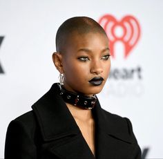 a woman with black lipstick and piercings on her face, wearing a black outfit