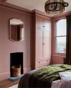 a bedroom with pink walls and green bedding in front of a mirror on the wall