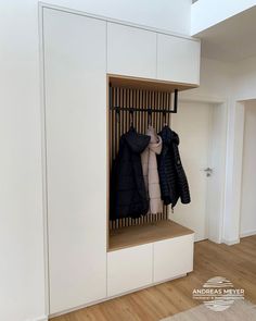 a coat rack with coats hanging on it in the corner of a room next to a door