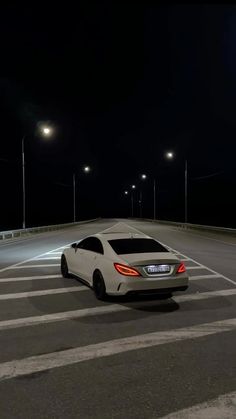 a white car is parked in the middle of an empty parking lot at night time