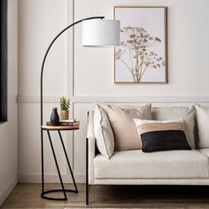 a living room with a white couch and a black lamp on the side table next to it