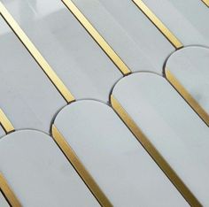 a close up view of some white and gold tiles with lines on the sides,