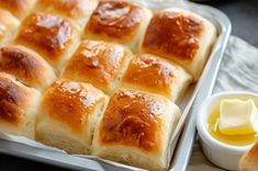 a pan filled with bread and butter next to a bowl of butter on the side