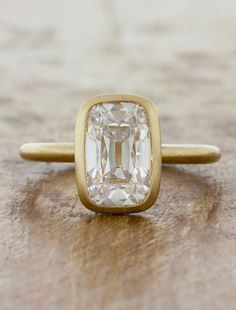 an old - fashioned diamond ring sits on a wooden surface