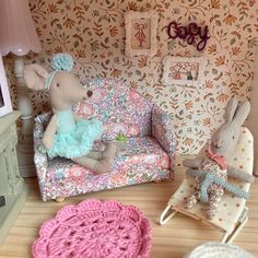 two stuffed animals sitting on top of a couch next to a wallpapered room