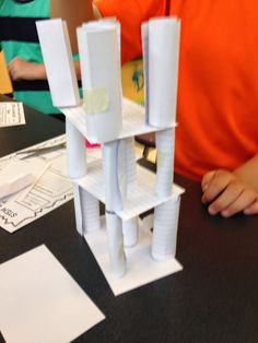 a person sitting at a table with some paper structures