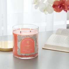 a pink candle sitting on top of a table next to an open book and flower