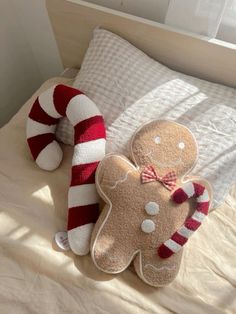 two stuffed gingerbreads and a candy cane on a bed